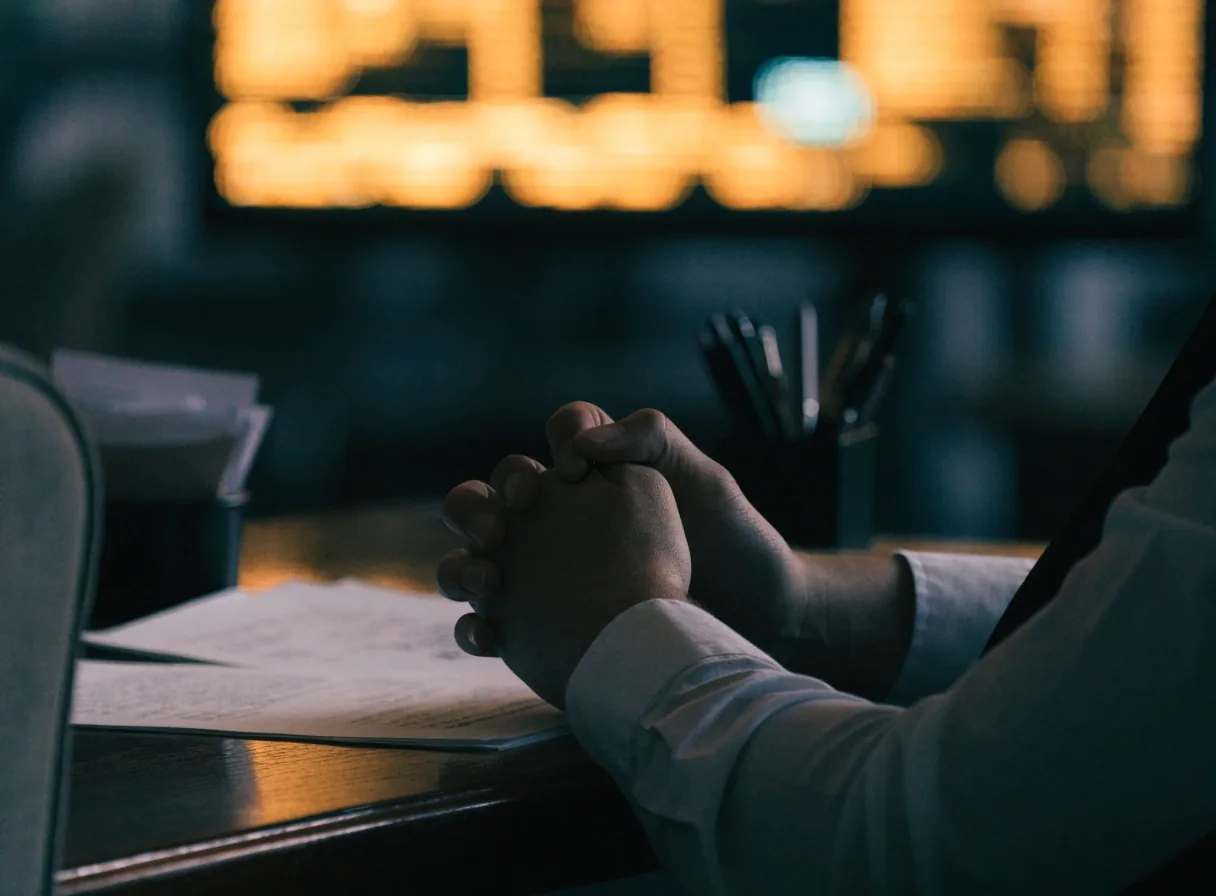 Hands on a trading desk at night lit by an out-of-focus screen glow
