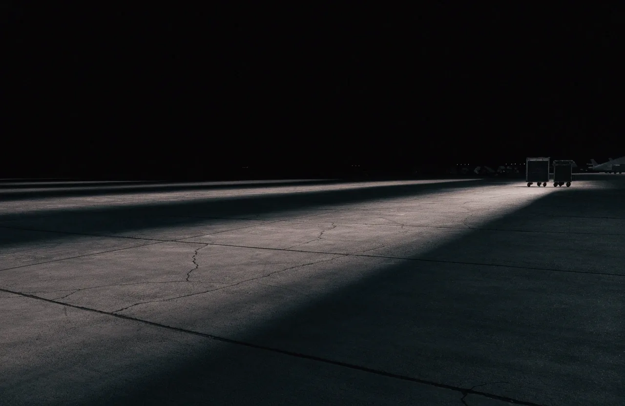An aircraft maintenance apron at night under a single work lamp
